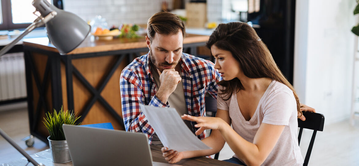 Frustrated couple checking bills at home using laptop