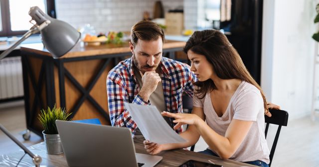 Frustrated couple checking bills at home using laptop