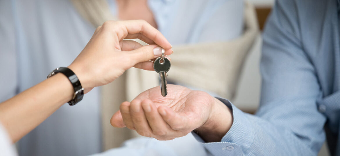 Couple of homeowners getting key to new house from realtor